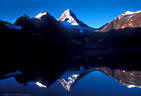 Early morning light reflects Assiniboine Peak in Lake Magog. Mount Assiniboine Provincial Park, British Colombia