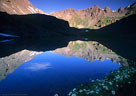 Surrounding peaks mirrored in Lower Clear Lake, with Marsh Marigolds.