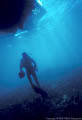 The sun silhouettes a scuba diver as he returns to the dive boat.